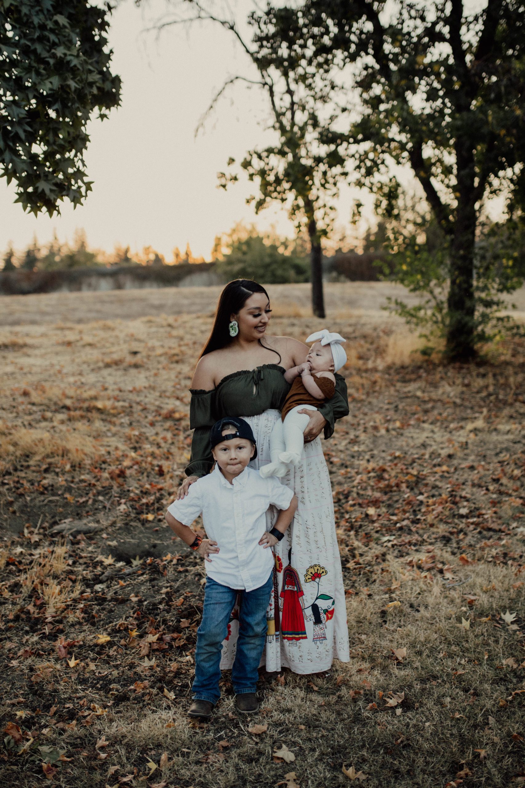 Photo of past awardee, Natalie Deanda, standing in a field with her two children.
